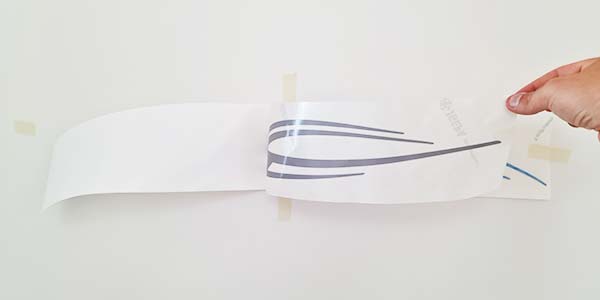 Knip de afplaktape aan de zijkant door en haal het motief van het rugpapier.